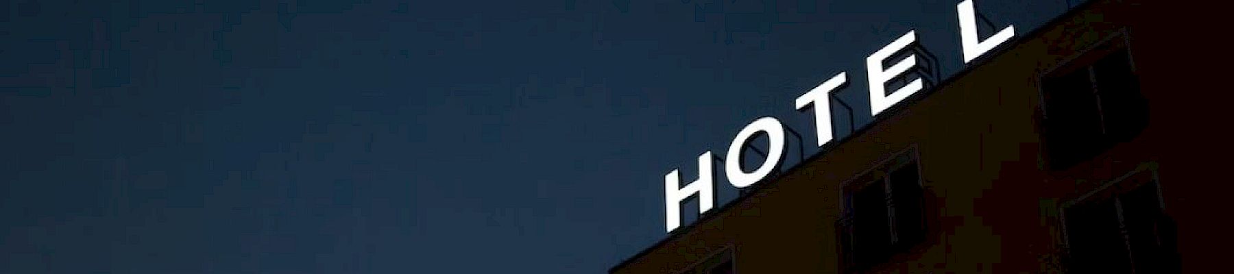 A hotel sign at night with lights for the letters "H", "O", "T", "E", and "L" on a building against a dark sky.