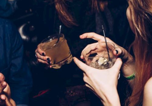 People are joyfully socializing with drinks in hand in a lively atmosphere.