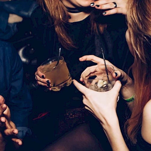 People are joyfully socializing with drinks in hand in a lively atmosphere.