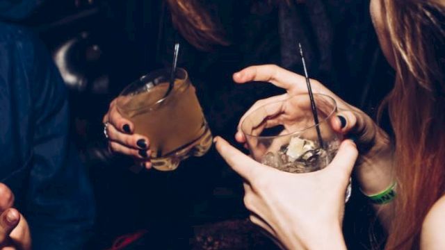 People are joyfully socializing with drinks in hand in a lively atmosphere.