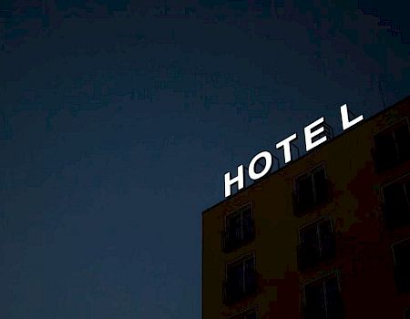 A hotel sign at night with lights for the letters "H", "O", "T", "E", and "L" on a building against a dark sky.