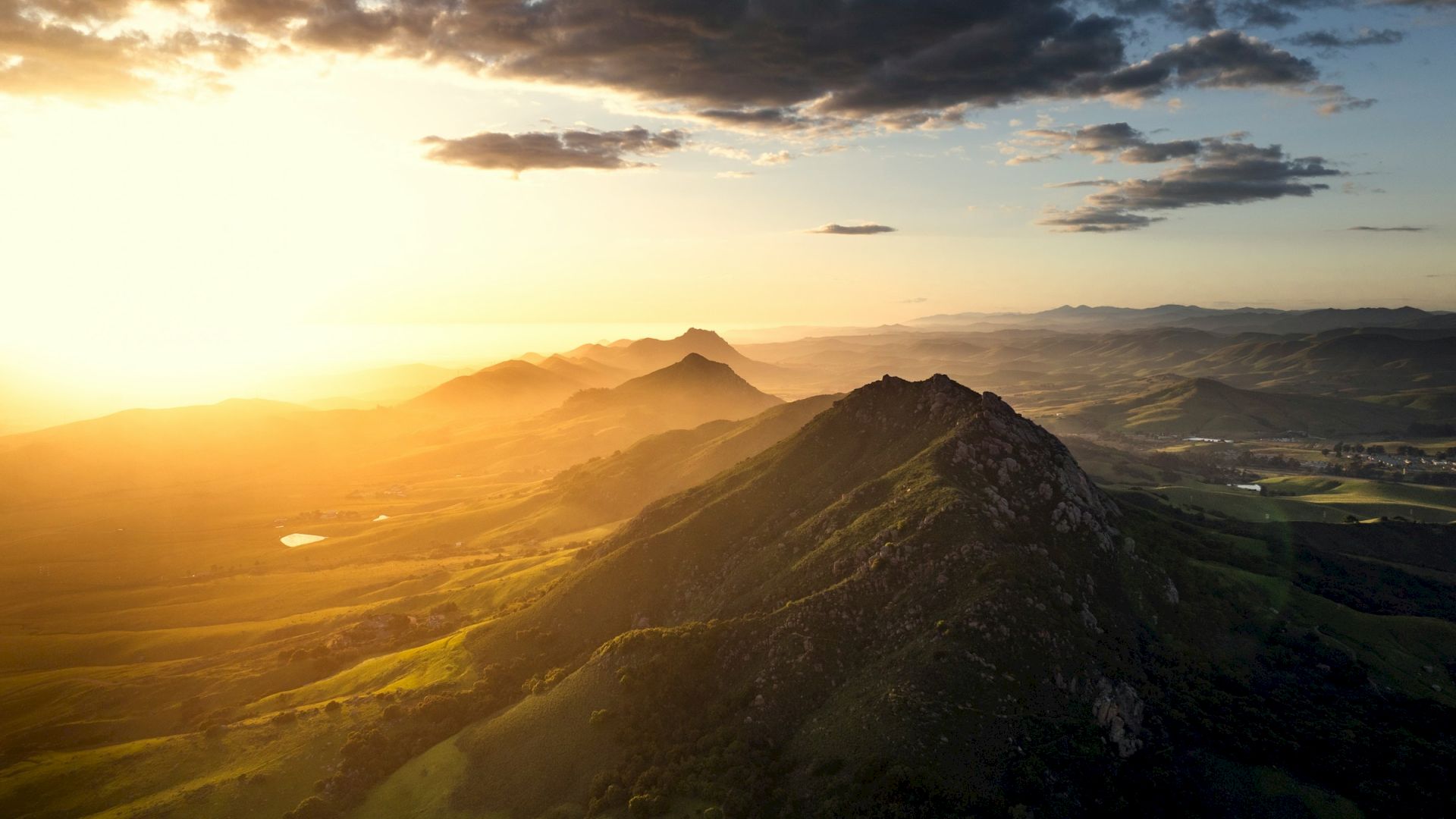 A beautiful mountainous landscape at sunset, with rolling hills and a glowing sky, offering a serene and picturesque view.
