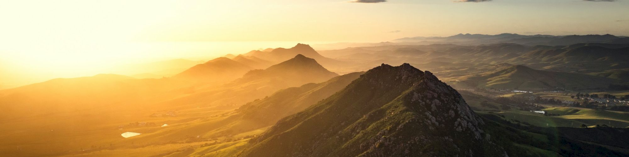A beautiful mountainous landscape at sunset, with rolling hills and a glowing sky, offering a serene and picturesque view.