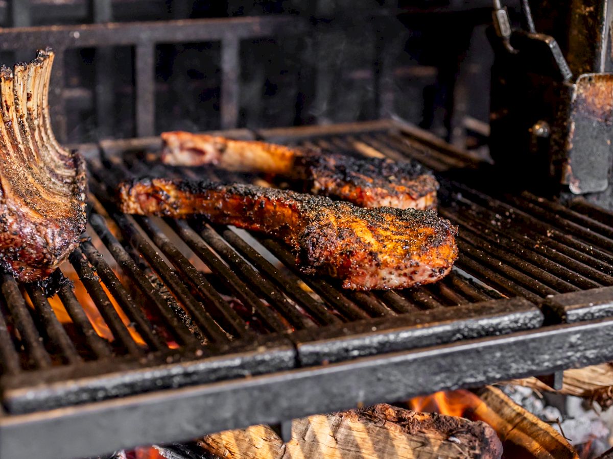 Juicy, grilled ribeye steaks on a hot barbecue with wood fire, showing a beautifully charred exterior.