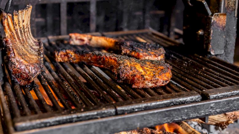 Juicy, grilled ribeye steaks on a hot barbecue with wood fire, showing a beautifully charred exterior.