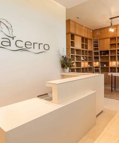 A spa reception area with a modern desk, decorative shelving, lighting, and a sign reading "spa cerro."