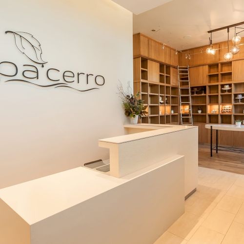 A spa reception area with a modern desk, decorative shelving, lighting, and a sign reading "spa cerro."