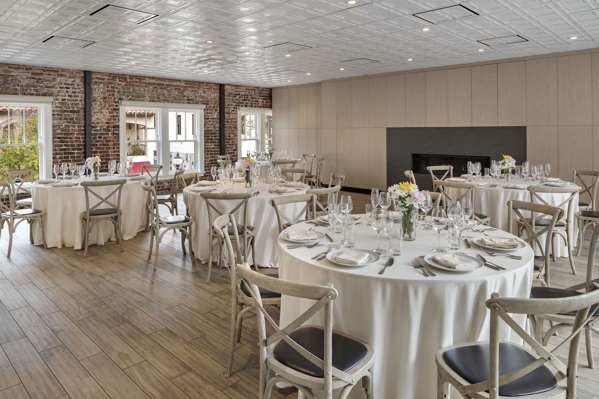 The image shows a well-decorated banquet hall with round tables set for a formal event, featuring flowers, plates, and glassware.
