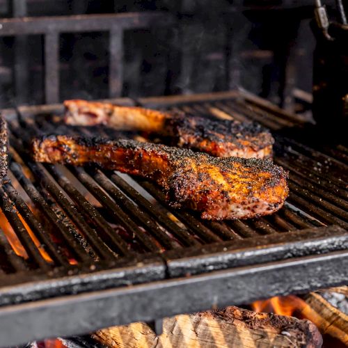 Grilled meat on a barbecue, including ribs and steaks, cooking over an open flame for a smoky, charred flavor.
