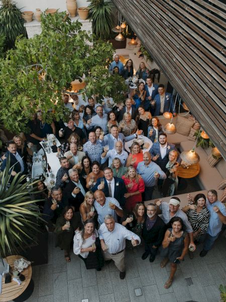 A decorated table with flowers and chairs in a bright room with brick walls and large windows.