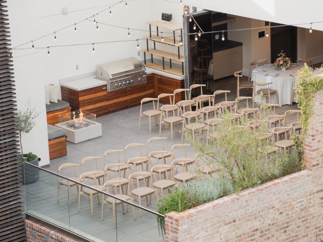 An outdoor venue setup with rows of chairs, lighting, and minimalist decor surrounded by brick walls, possibly for an event or gathering.