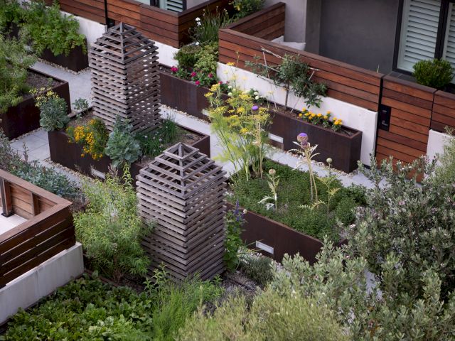 The image shows a rooftop garden with wooden planters, greenery, and trellises, creating a serene and organized urban oasis.