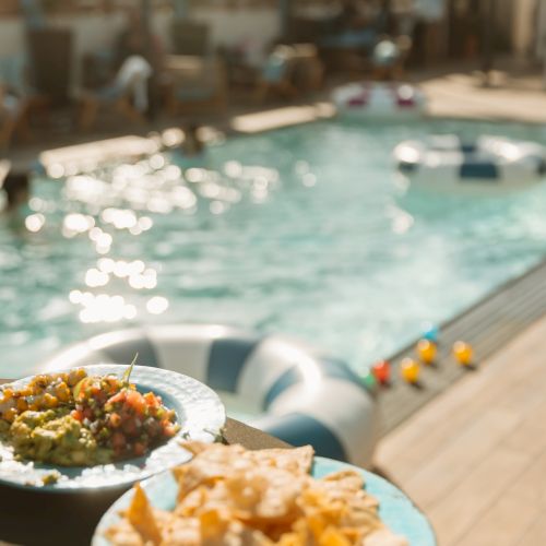Poolside patio scene with a refreshing swim and plates of snacks by the turquoise pool.