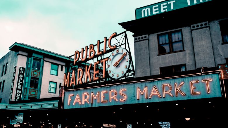 The image shows a vintage-style sign for a "Public Market" and "Farmers Market" on the exterior of a building, with a clock above.